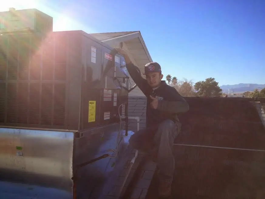 HVAC technician performing Air Duct Cleaning on a rooftop unit in Russellville